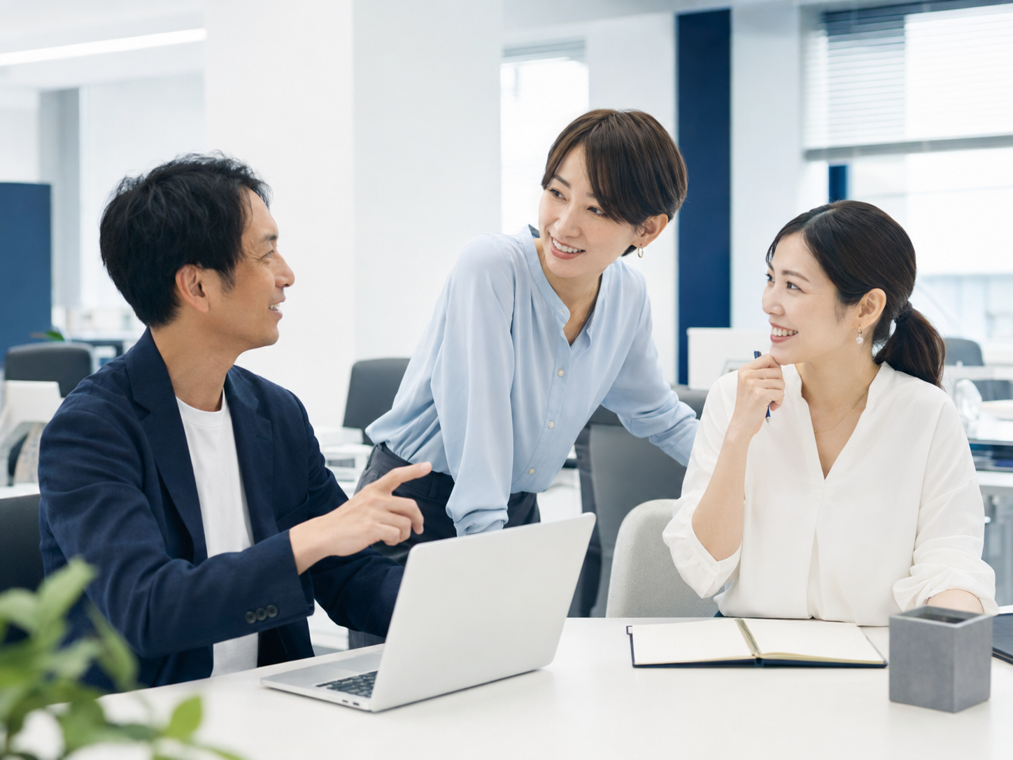 オフィスで笑顔で話し合いながら働くスタッフたちの様子